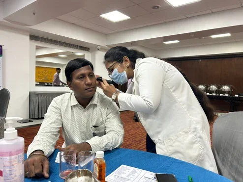 Doctor performing ear examination at Lions Club health camp